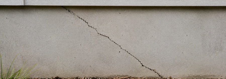 Diagonal crack across home's concrete foundation wall, type of foundation cracks in Gainesville, FL, caused by uneven soil settling.