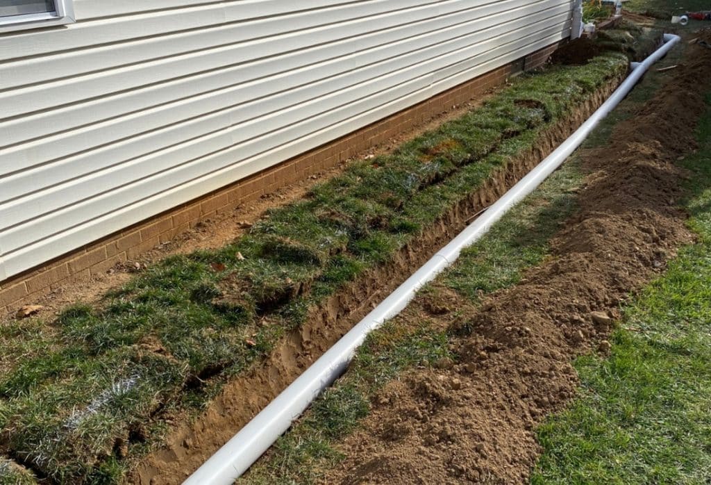 French drain foundation drainage system in Ocala, FL, with perforated pipe filter sock and crushed gravel installed along a concrete block home.