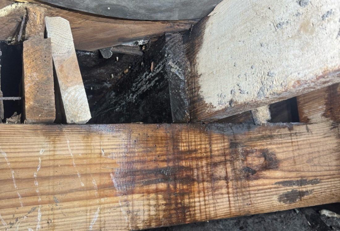 Moisture-damaged crawl space floor beam and joists showing heavy water staining and wood deterioration in Callahan, FL.