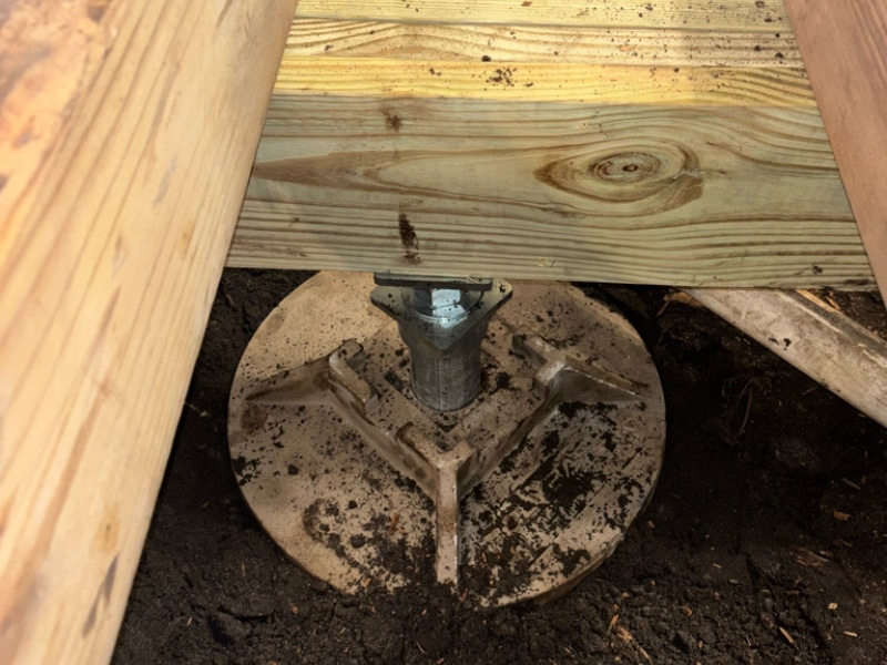 Galvanized adjustable stabilizer post installed on pre-engineered footing pad under floor beam in Callahan, FL.