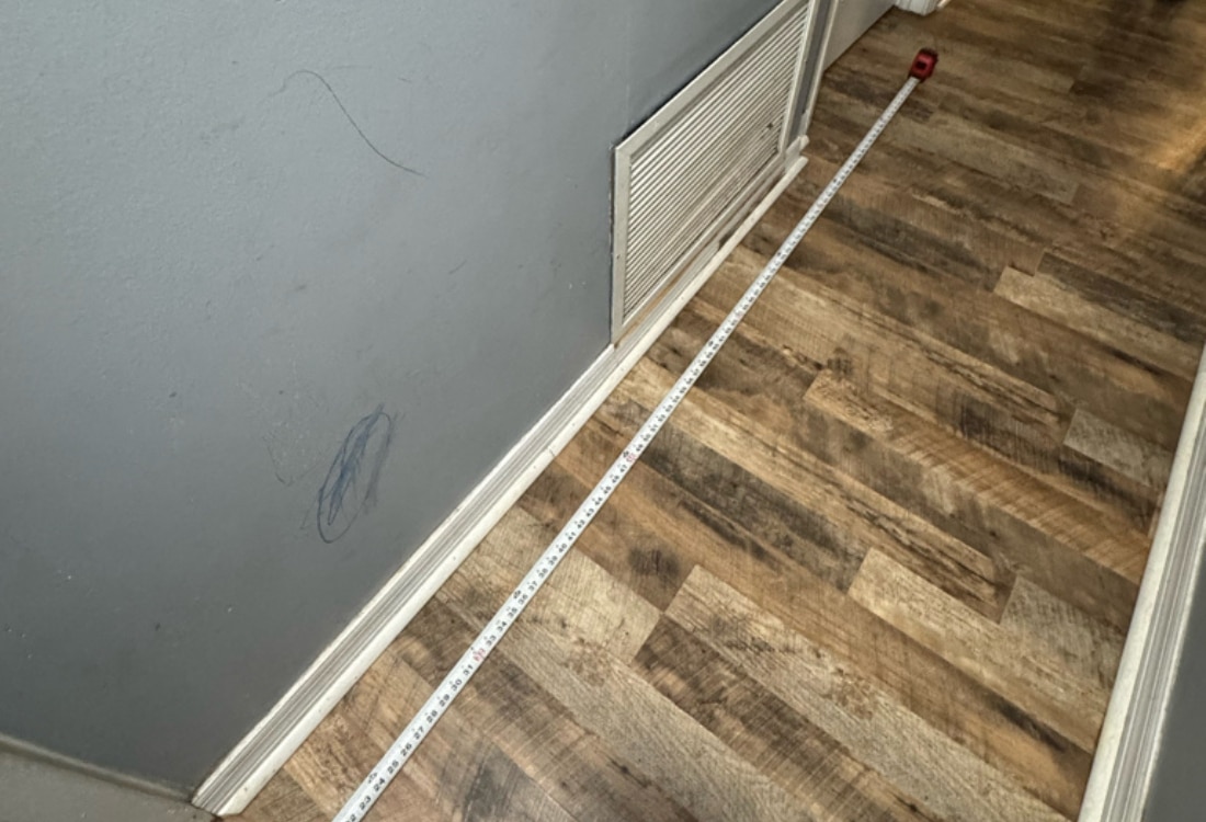Level tool placed on wooden floor showing uneven surface before crawl space floor repair in Callahan, FL.