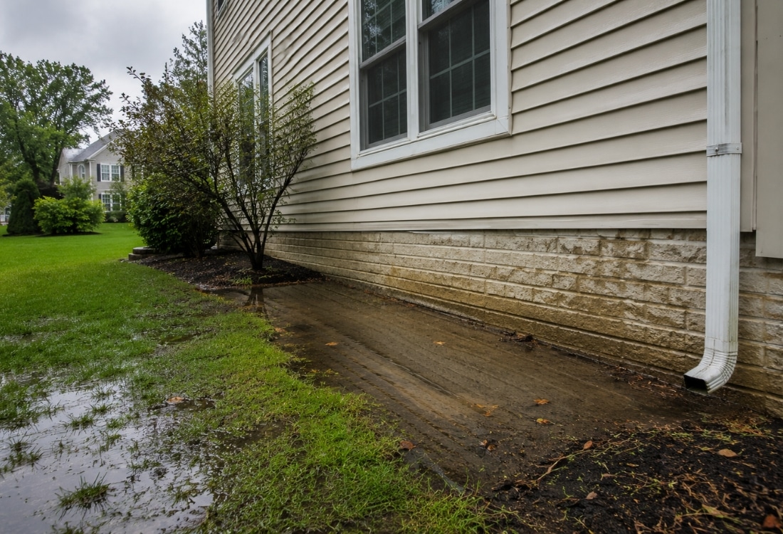 Standing water pooling against home foundation after heavy rain a sign that short downspout in damage foundation in Ocala, FL.