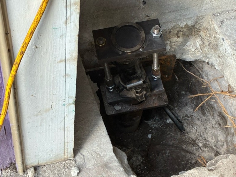Helical pier bracket installed at foundation footing for load transfer during foundation repair in Neptune Beach, FL.