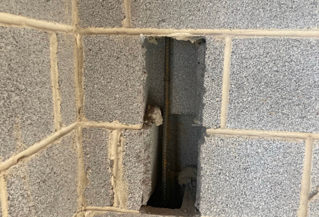 Rebar pins installed in a block foundation wall to lock and reinforce, a bowed foundation wall repair method in Ocala FL.