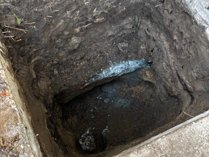 Open excavation pit exposing foundation footing at commercial building before push pier installation in Jacksonville, FL.
