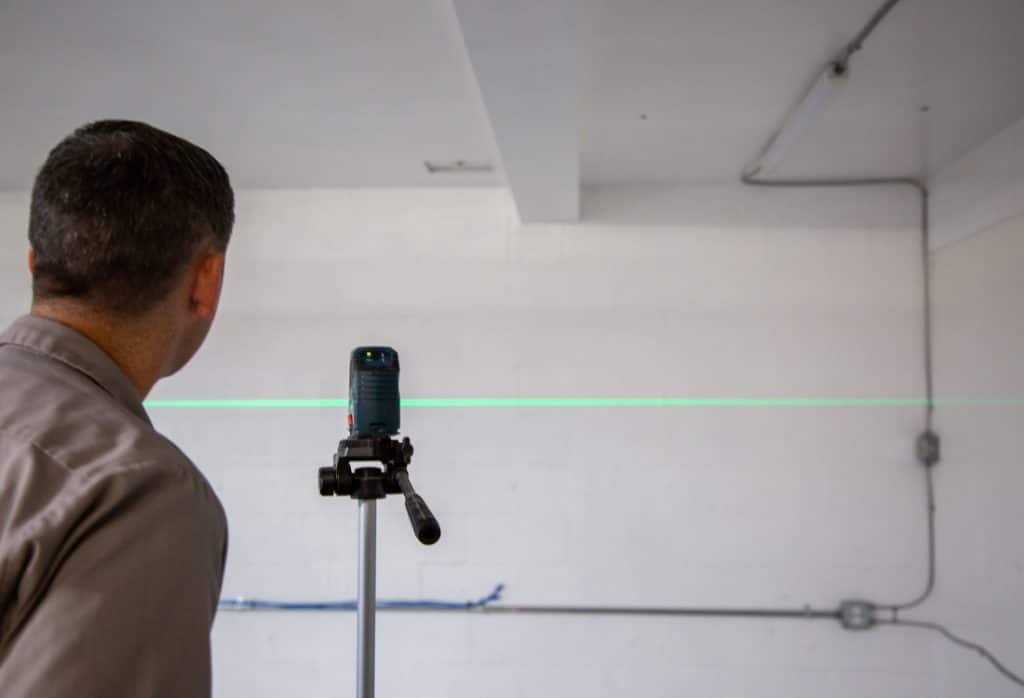 Foundation specialist uses a laser level to check the extent of damage that affects carbon fiber foundation repair cost in Ocala FL