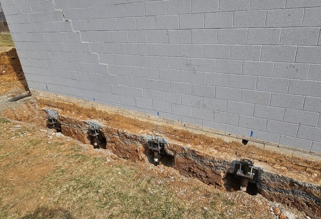 Push pier brackets installed along foundation footing to stabilize settlement and fix foundation cracks in Palm Coast, FL.