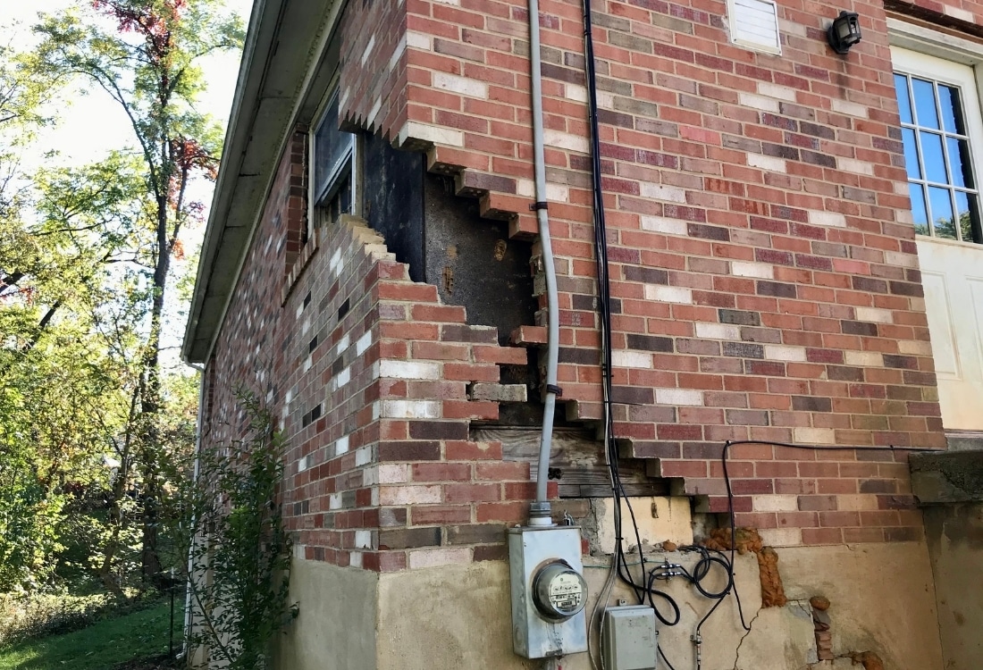Brick home exterior showing severe structural collapse from unrepaired foundation cracks in Gainesville, FL, due to settlement.