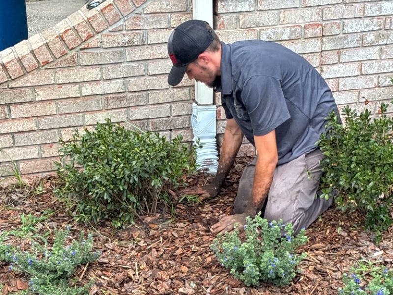 LUX crew hand backfilling open trench after underground pipe installation during downspout drainage system work in Jacksonville, FL.